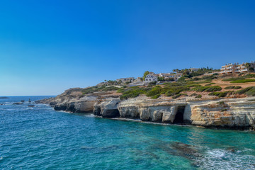 Fototapeta na wymiar View of the blue water of the Mediterranean Sea and coastal cliffs on the coast of the island of Cyprus. Sunny hot day at the coastline near the town of Paphos.