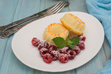 Curd muffins with raspberries and mint on a white ceramic plate.