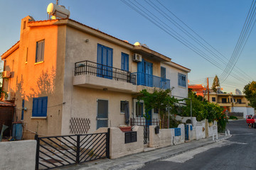 Typical residential building in the city of Paphos, Cyprus.  The facade of the house with light cladding and blue doors and windows.  Private house with a balcony.