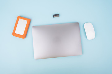 Top view of Laptop or Notebook with white mouse , external hard disk and thumb or usb drive isolated on blue pastel background