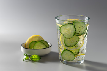 chia seeds water with cucumber and lemon in a glass on a gray background. diet, weight loss...