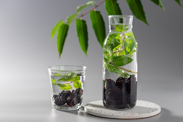 fresh infused water with mint and blackberries in a bottle and glass. healthy nutrition diet concept. Gray background. copy space