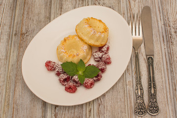 Curd muffins with raspberries and mint on a white ceramic plate.