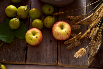 Composition of village red apples and small pears on a wooden table