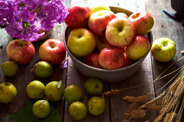 Composition of village red apples and small pears on a wooden table