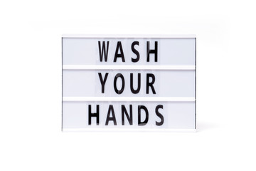 Wash your hands. Text on a vintage lightbox display placed on a white table on a light background. 