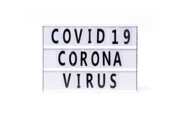 Covid 19 corona virus. Text on a vintage lightbox display placed on a white table on a light background. 