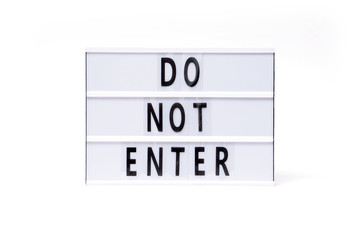Do not enter. Text on a vintage lightbox display placed on a white table on a light background. 