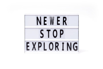 Newer stop exploring. Text on a vintage lightbox display placed on a white table on a light background. 