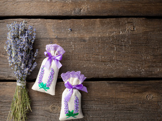 sachet with dried lavender, decorated with a ribbon and a bouquet of lavender on a dark wooden...