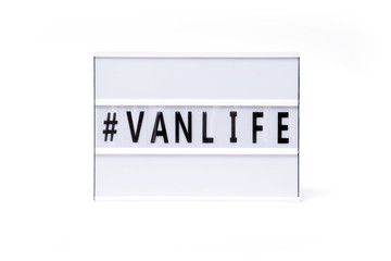 Hashtag Vanlife. Text on a vintage lightbox display placed on a white table on a light background. 