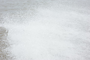 Water splashes from the propellers of a long tail boat.