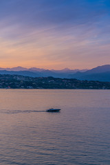 A boat in the sunset with the silhouettes of the mountains in the background on Lake Garda, Italy