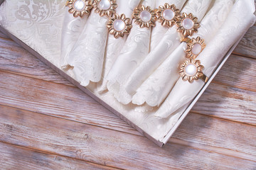 The napkin box is decorated with brooches on wooden background. Set of the napkins. Wedding table...
