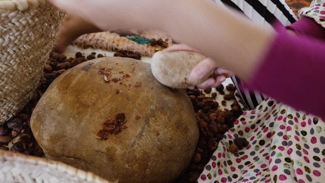 A Moroccan woman opens Argan nuts to extract the kernels for the traditional handmade Argan oil production. The oil is rich in fatty acids and is used in cooking and cosmetics.