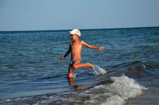 A happy child jumps over a sea wave. A happy boy enjoys the sea. A cheerful little boy is bathing in the sea. Coast. Rest. Summer.
