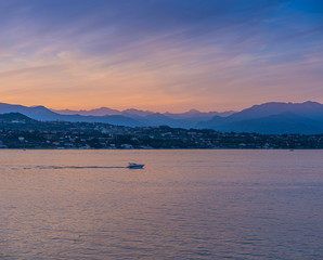 A boat in the sunset with the silhouettes of the mountains in the background on Lake Garda, Italy