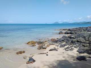 Idyllic landscape of the calm caribbean sea with rocks in the sand on the beach under tropical blue...