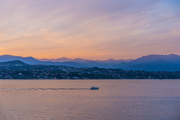 A boat in the sunset with the silhouettes of the mountains in the background on Lake Garda, Italy