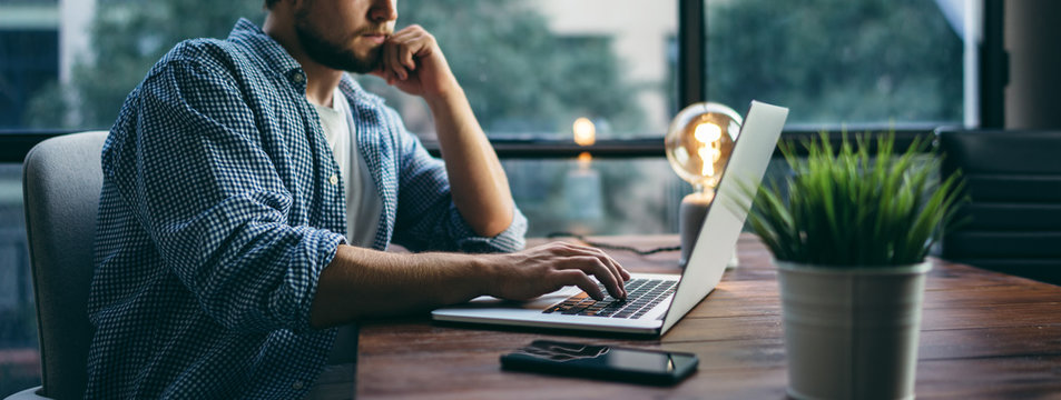 Young Man Working With A Laptop. Freelancer Connecting To Internet Via Computer. Businessman At Work