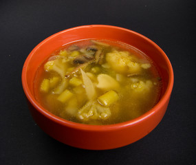 Chicken soup with vegetables in red bowl on dark background. Healthy food. Food for cold weather. Winter or fall food