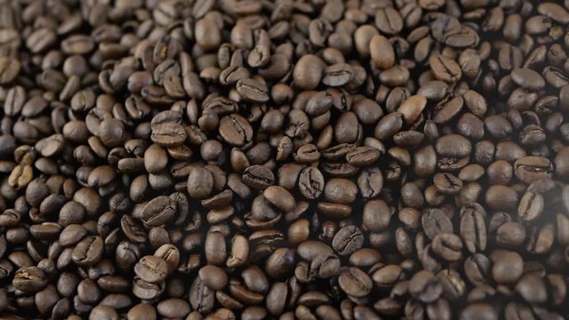 Beautiful roasted grains,aromatic coffee with smoke,close-up.Camera slide