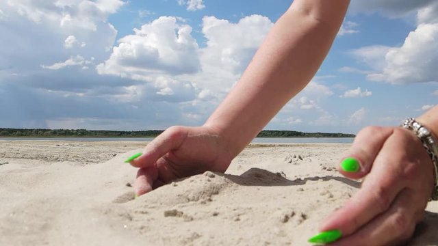 Video, female hands scatter white sand on the beach on a sunny hot day