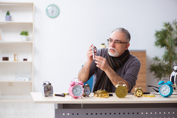 Old male watchmaker working in the workshop