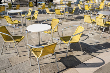 Empty restaurant tables in Venice Italy with yellow chairs