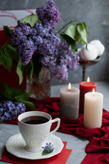 Fototapeta na wymiar Atmospheric photo: black coffee and a white cup, a bouquet of lilacs, a few large candles, marshmallows on a gray background