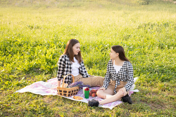 Two happy girls sit on the grass in the summer in the Park
