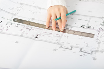 Architect working on blueprint, with architectural project at construction site at office desk in office