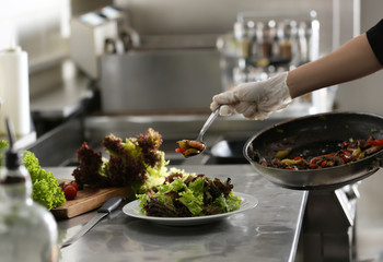 Female chef cooking tasty food in restaurant kitchen, closeup