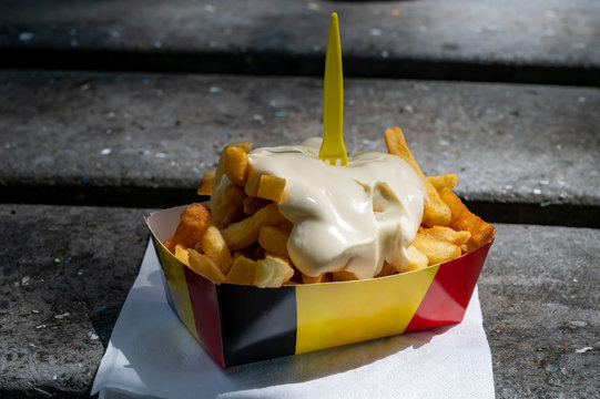 Paper box in colors of Belgian flag with fried potato frit chips and mayonnaise sauсe.