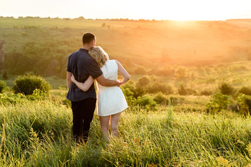 young couple in the field watching the sunset