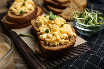 Tasty scrambled egg sandwiches on wooden board