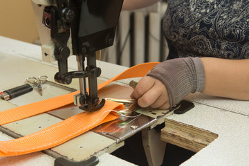 Industrial sewing machine sews a webbing sling. Manufacture of textile slings and tie straps.