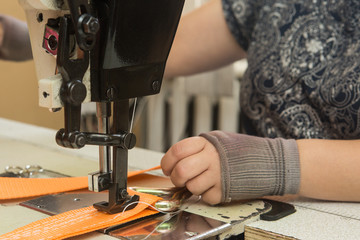 Industrial sewing machine sews a webbing sling. Manufacture of textile slings and tie straps.