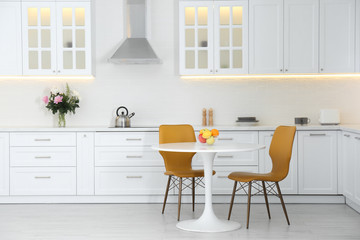 Table with orange chairs in modern kitchen interior