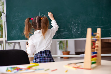Small girl in front of blackboard in the classroom