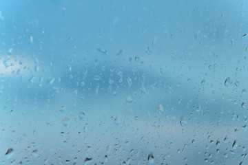 Abstract Rain Water Droplets on Glass Window with a Blue Sky Background