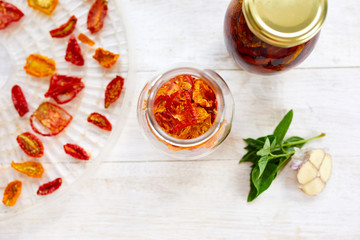 Homemade sun dried tomatoes with herbs, garlic in olive oil in a glass jar