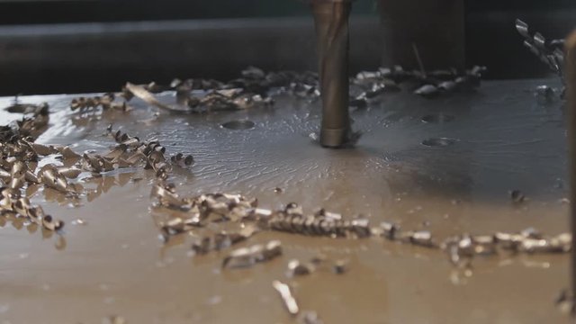 Industrial drill drilling an iron plate.