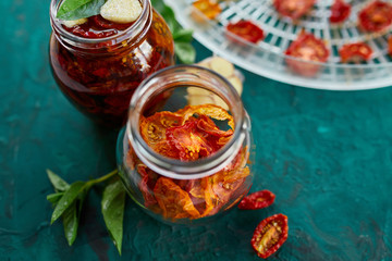 Homemade sun dried tomatoes with herbs, garlic in olive oil in a glass jar