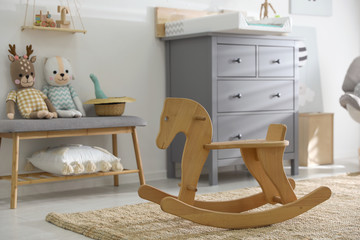 Beautiful baby room interior with toys, rocking horse and modern changing table