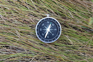 round compass on background of summer grass as symbol of tourism with compass, travel with compass...