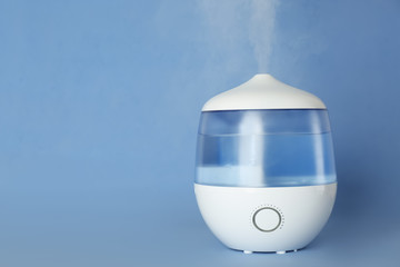 Modern air humidifier on light blue background. Space for text