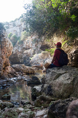 Virgin nature, travel, adventurism. A man is resting sitting on a stone