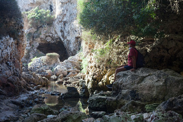 Virgin nature, travel, adventurism. A man is resting sitting on a stone