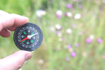Old classic navigation compass in hand on natural background as symbol of tourism with compass,...
